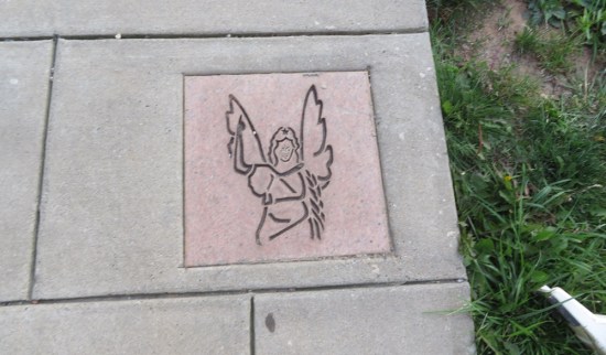 Etched angel picture installed in the middle of a sidewalk panel.