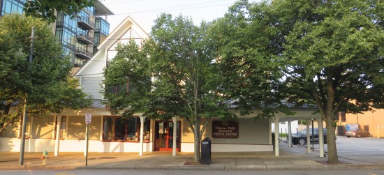 Museum visitor center with trees lining the sidewalk in front of it.