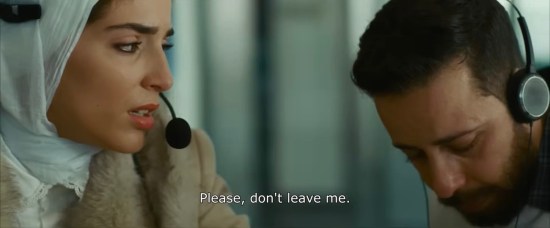 Two Palestinian call center reps listening to someone on phone who says, "Please, don't leave me."