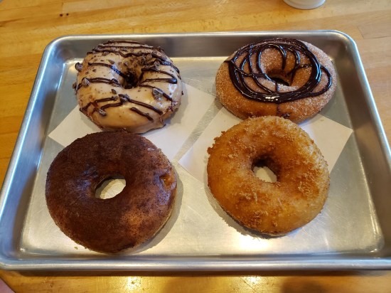 Four donuts on metal pan with liner, refer to caption.