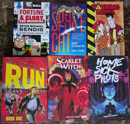 6 Graphic Novels on brown kitchen table, refer to next six capsules.