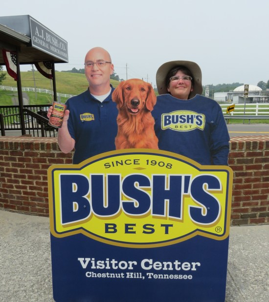 Anne on her tiptoes to pose behind a cardboard standee of Jay Bush and Duke.