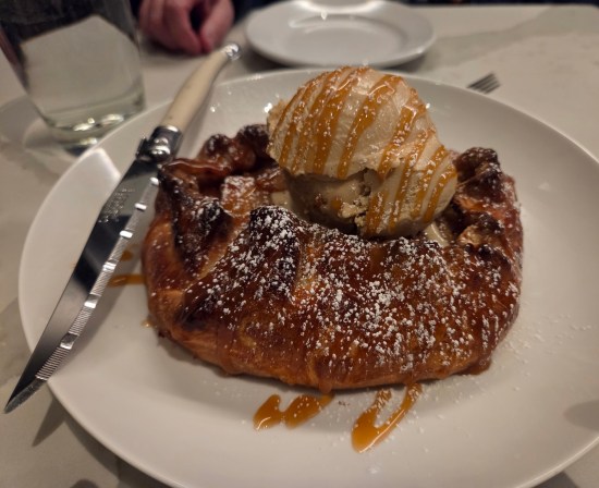 Apple pastry with yummy gelato scoop on top. A knife lies on the plate for size context.
