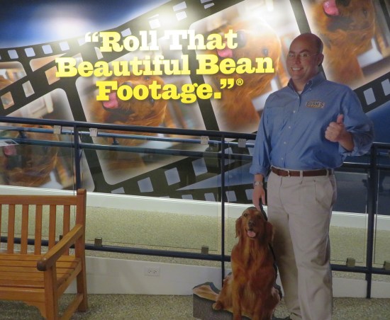 Cardboard standee of Jay and Duke indoors, by a wall with the phrase "Roll That Beautiful Bean Footage" in big yellow letters on the wall.