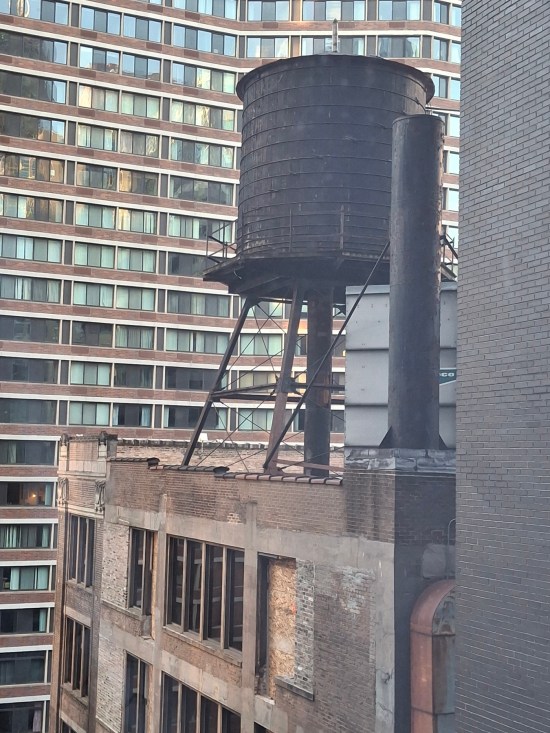Actual downtown water tower atop a high building, with even taller buildings behind it.