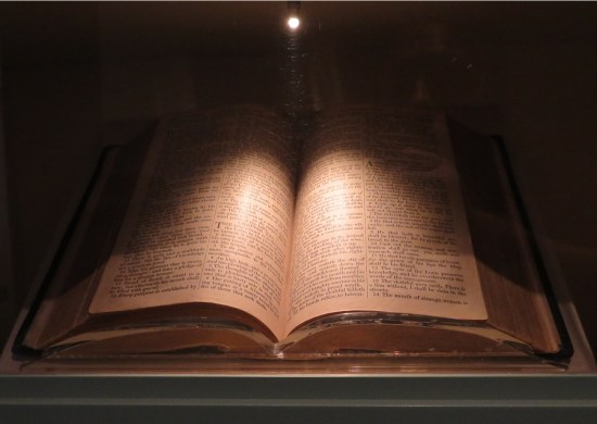 Large Bible in glass case, very shadowed with a pinpoint light above it.