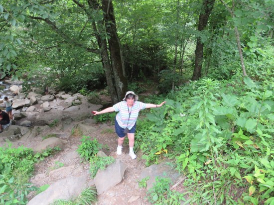 Anne walking uphill from a pretty creek, a bit precariously.