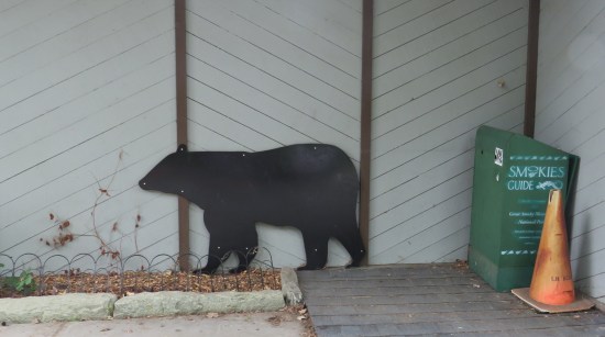 wooden bear silhouette against a gray outside wall.