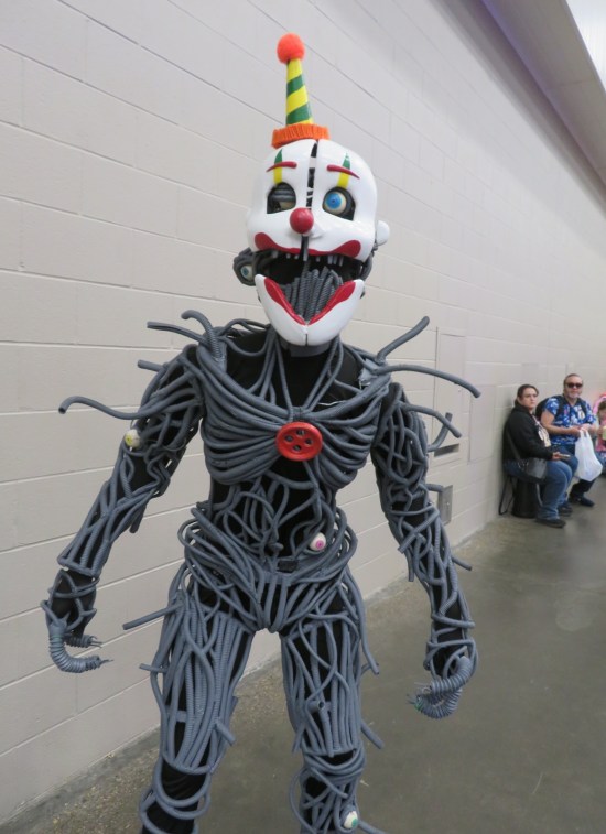 Robot costumer covered in tubes and cord, plus creepy clown mask and hat.