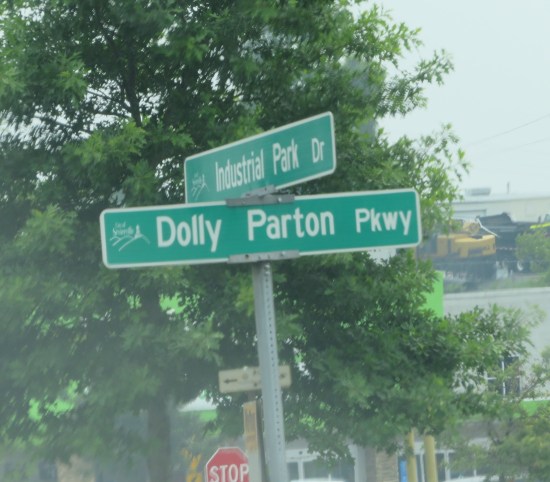 Green street sign for Dolly Parton Parkway at the intersection of Industrial Park Drive.