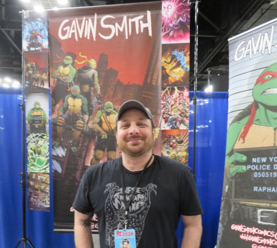 Gavin Smith at his table with lots of TMNT art around him.