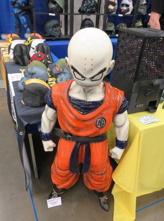 short bald Goku statue with a four-digit price tag, standing at a booth selling character helmets.