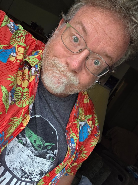 Me wearing a gray T-shirt with Baby Yoda that says "Star Wars" under him. Over that I'm wearing an orange tropical shirt covered in Mandos and Grogus.