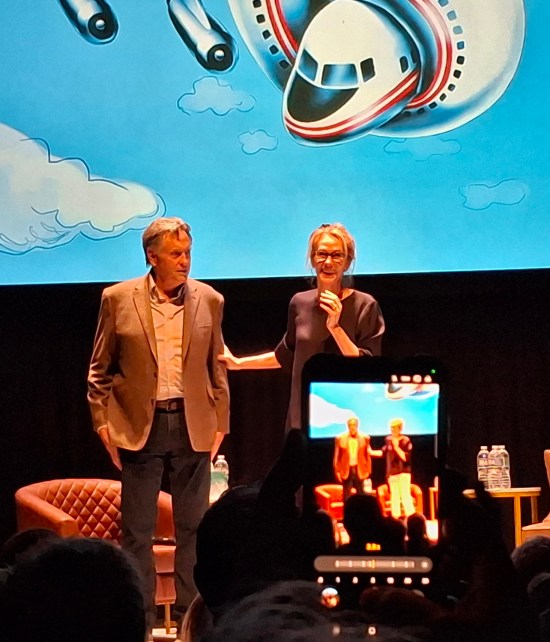 Robert hays and Julie Hagerty viewed through someone else's phone in a darkened theater.