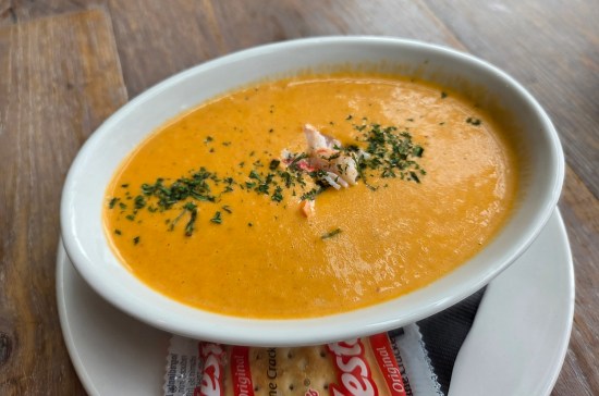 lobster bisque in shallow oval bowl, colored like pumpkin.