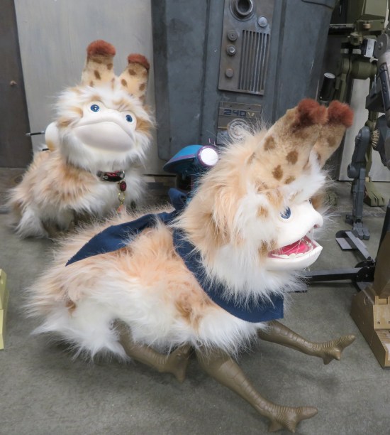 Two large stuffed Loth-cats sitting on gray floor.