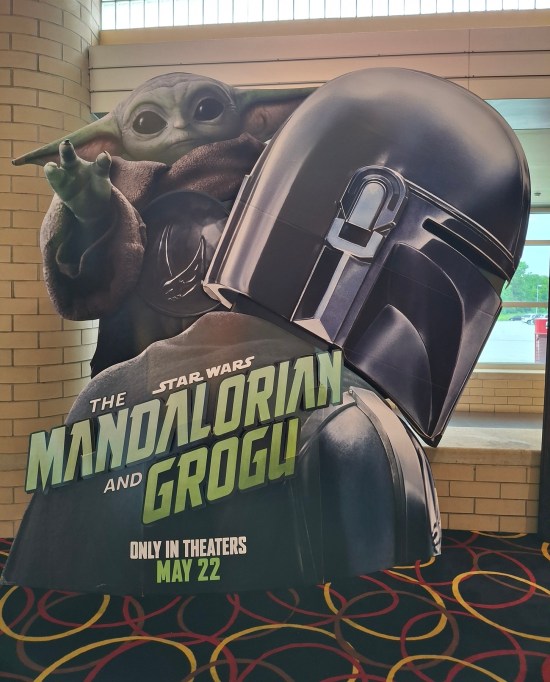 Cardboard theater standee for The Mandalorian and Grogu, with Baby Yoda perched on Mando's shoulder.