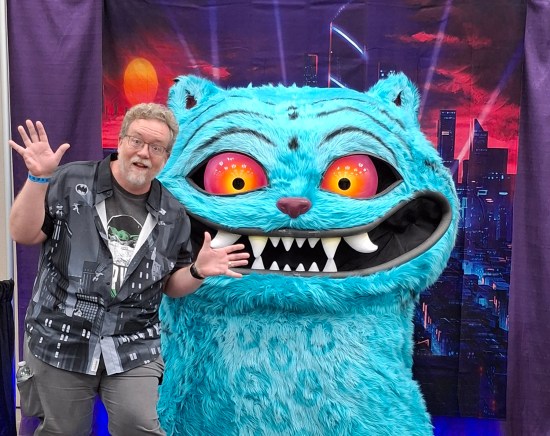 me doing jazz hands in front of a giant replica of Derpy the magic blue cat from "KPop Demon Hunters".