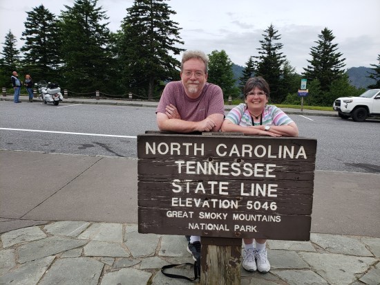 Me and Anne posing behind a wooden sign on a mountain road: "North Carolina - Tennessee state line, elevation 5046 feet, Great Smoky Mountains National Park