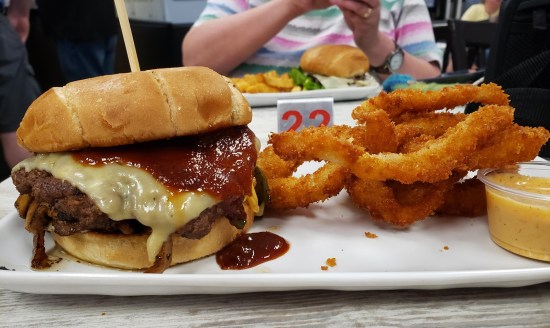 big burger served with onion rings, refer to caption.