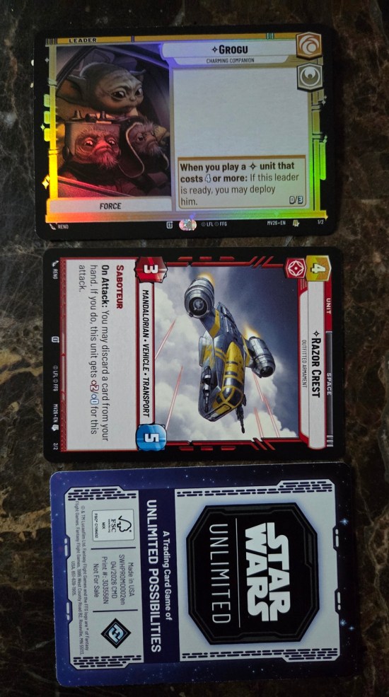 Three trading cards from the new Star Wars Unlimited game -- one for Grogu, one for the Razor Crest, and one with just the game's logo.