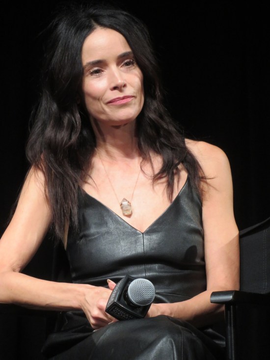 Abigail Spencer sitting on dark stage in black dress.