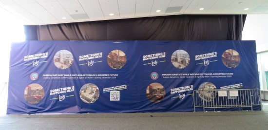 Convention Center entrance covered by black tarp, covered in turn by a blue tarp with images promising new stuff coming soon to Indy.