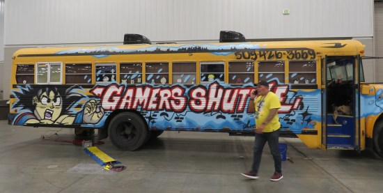 School bus that says "Gamers Shuttle" on the side. Some dude walked in front of it.