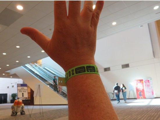 Holding up my hand with my ICC wristband in front of R5-D4 and escalators.