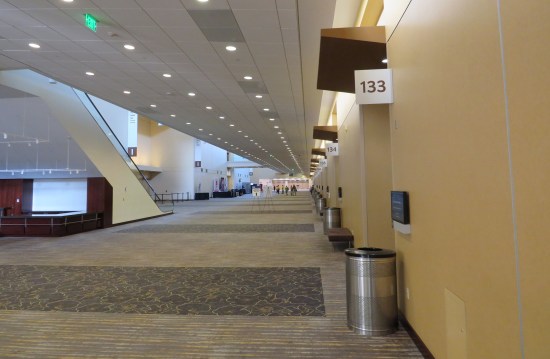 Long shot of a convention center hallway with various architectural protuberance. One wall is a pale, uniform yellow.