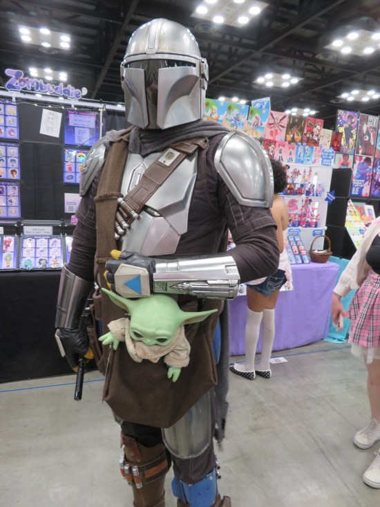 Mandalorian cosplayer with Grogu doll