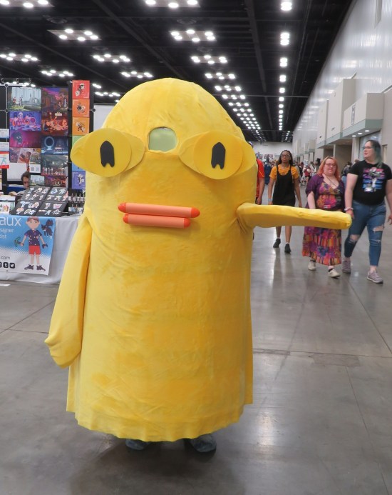 Large yellow hill-shaped costume with two pink crayons for lips and thin arms that don't bend.