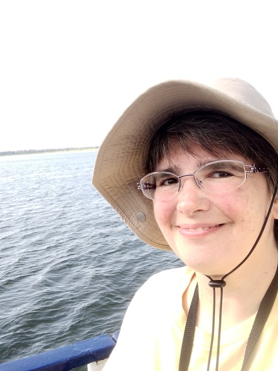 Anne in hat, smiling while boating through Charleston harbor selfie!