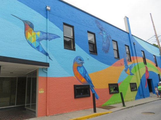Blue mural with colorful strip cutting through the bottom. Above are painted five large birds.