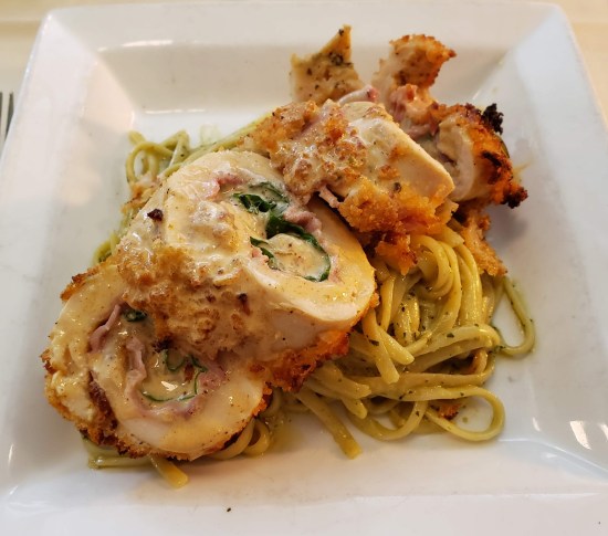 chicken cordon bleu served on square white plate with pasta.