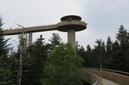 Concrete observation tower atop a forested mountain.