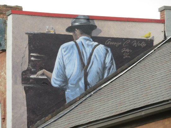 George C. Wolfe mural, him seated at a black upright piano with his back to us.