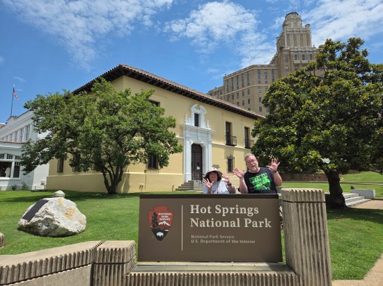 Us doing jazz hands behind the main entrance sign to Hot Springs National Park.