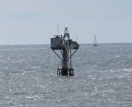 Tall mechanical construct sticking out of ocean water.