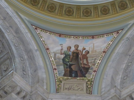 Greek-style ceiling painting of a shirtless blacksmith in an apron, a woman in a green toga wielding a caduceus, and another shirtless guy with a barrel or drum.