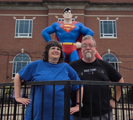 Us posing like Superman in front of a statue of him.