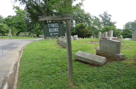Wooden sign on post in cemetery labeled "Daniel Boone" with arrow pointing left.