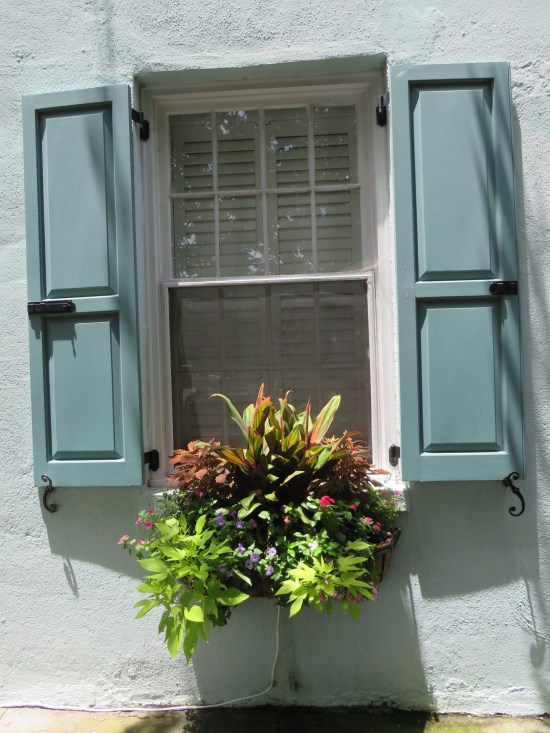 windowsill planter on a blue house, filled with pretty flowers.