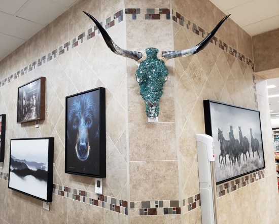 Bejeweled turquoise cow skull hanging high above the corner of a bathroom hallway.