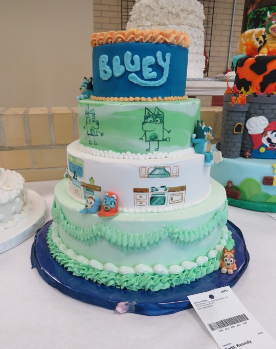 4-layer white and teal cake with Bluey decorations.