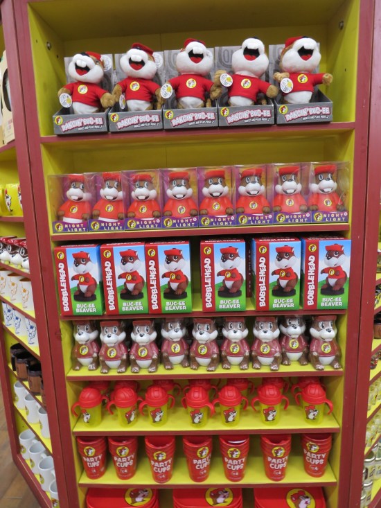 Tall bookcase with different Buc-ee items on each shelf.