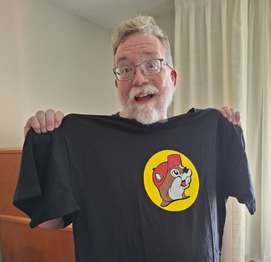 Me holding up a black T-shirt with Buc-ee's head in a yellow circle.