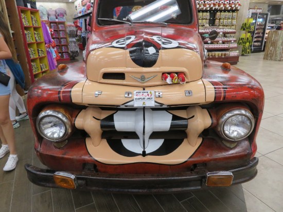 Old red truck with front painted to resemble Buc-ee's distorted face.