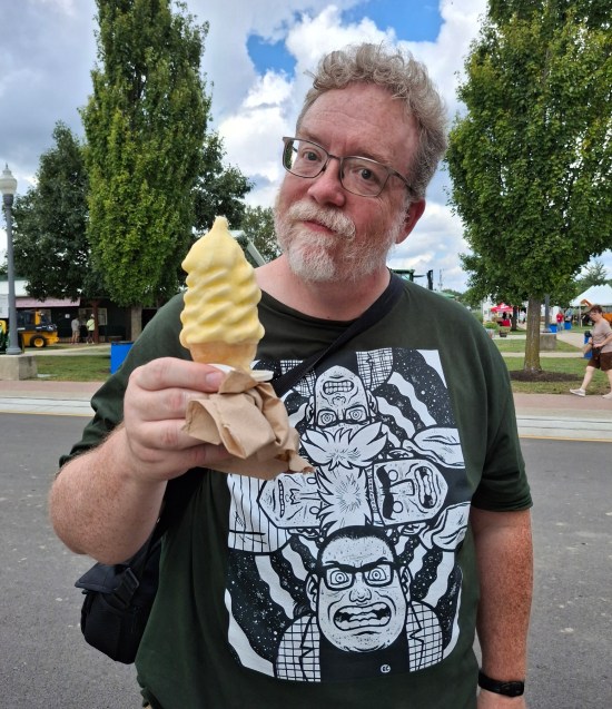 Me holding a yellow soft-serve Ice Cream Cone, not smiling.