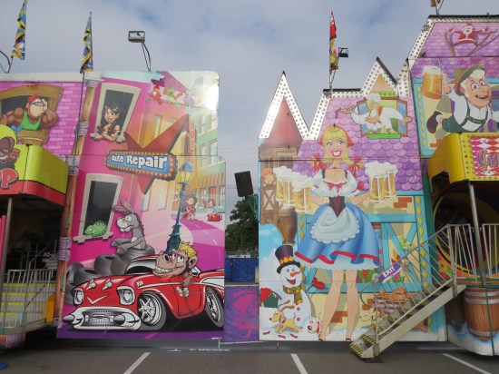 Two fun houses next to each other, one with street-racing cartoon animals and one with a cartoon German beer hall theme.